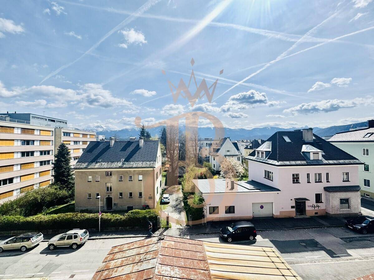 Weitläufiger Blick über eine Wohngegend mit geparkten Autos und einer beeindruckenden Bergkulisse.