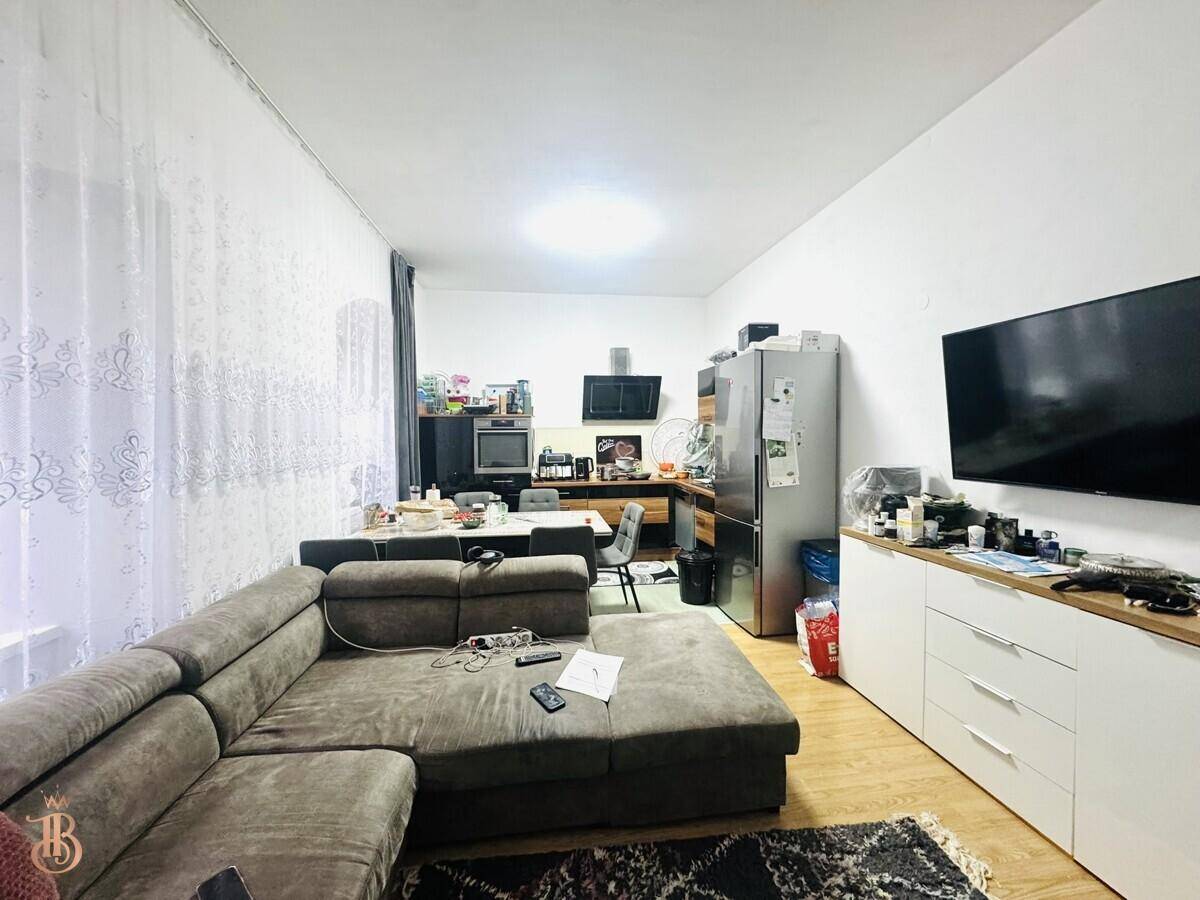 Offene Wohnküche mit großem Sofa, Essbereich und Kühlschrank, ideal für geselliges Beisammensein.
