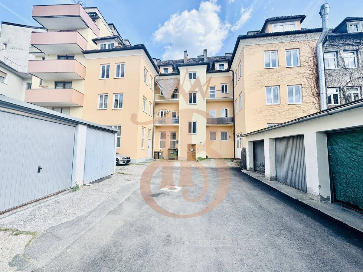 Rückansicht eines Mehrfamilienhauses mit Garagen und einem Innenhofbereich.