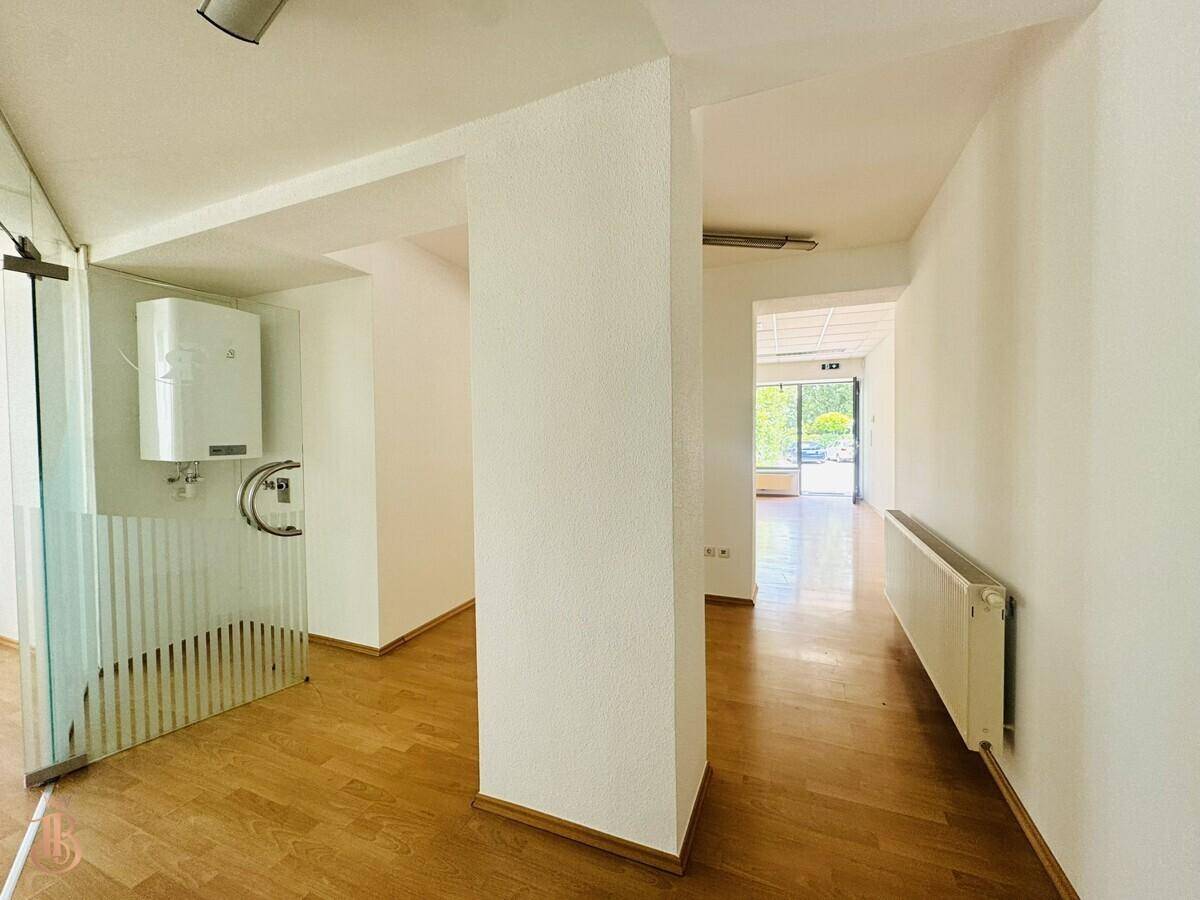 Heller Eingangsbereich mit Glaswand, Laminatboden und Warmwasserbereiter, führt zu offenen Räumen.
