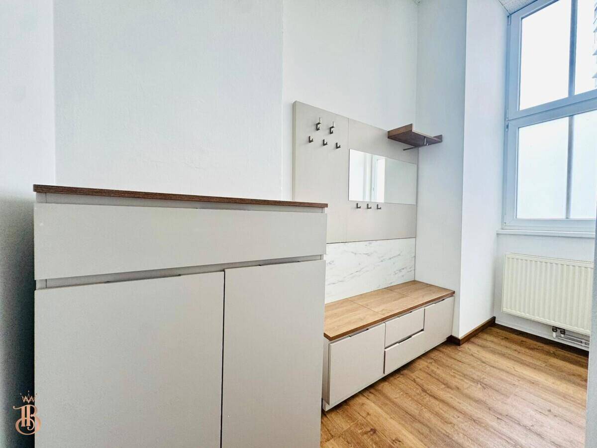Eingangsbereich mit Garderobe, Fenster und Heizkörper, ausgestattet mit Laminatboden.