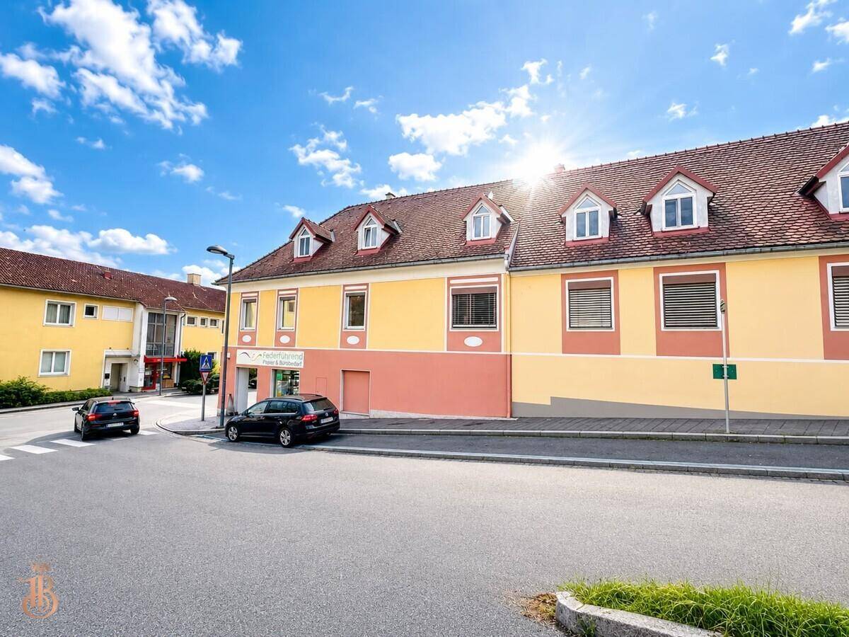 Sonnige Seitenansicht des Gebäudes mit gelber Fassade und roten Dachziegeln.