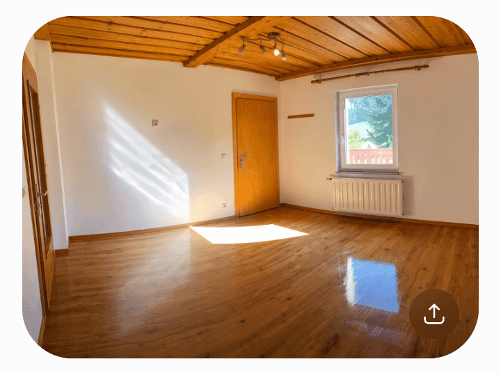 Geräumiges Zimmer mit Holzbalkendecke, glänzendem Parkettboden und viel natürlichem Licht.