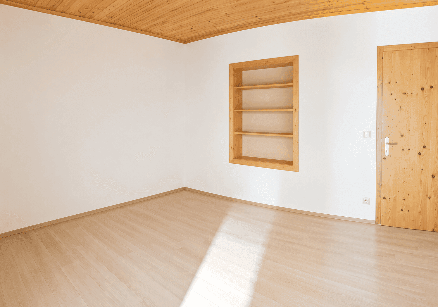 Helles Zimmer mit hellem Holzboden, Holzdecke und einem praktischen Einbauregal.