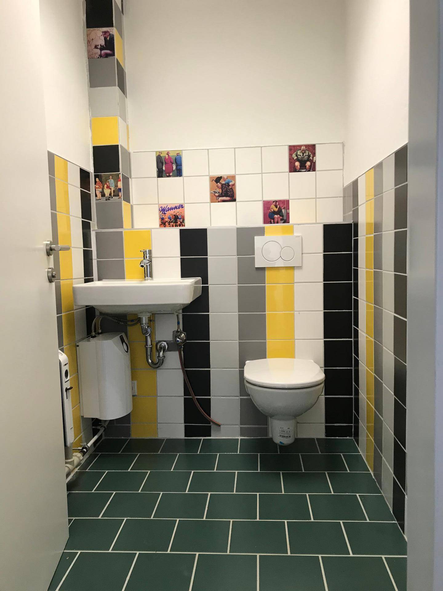 Modernes Gäste-WC mit farbigen Fliesen, Waschbecken und wandhängendem WC.