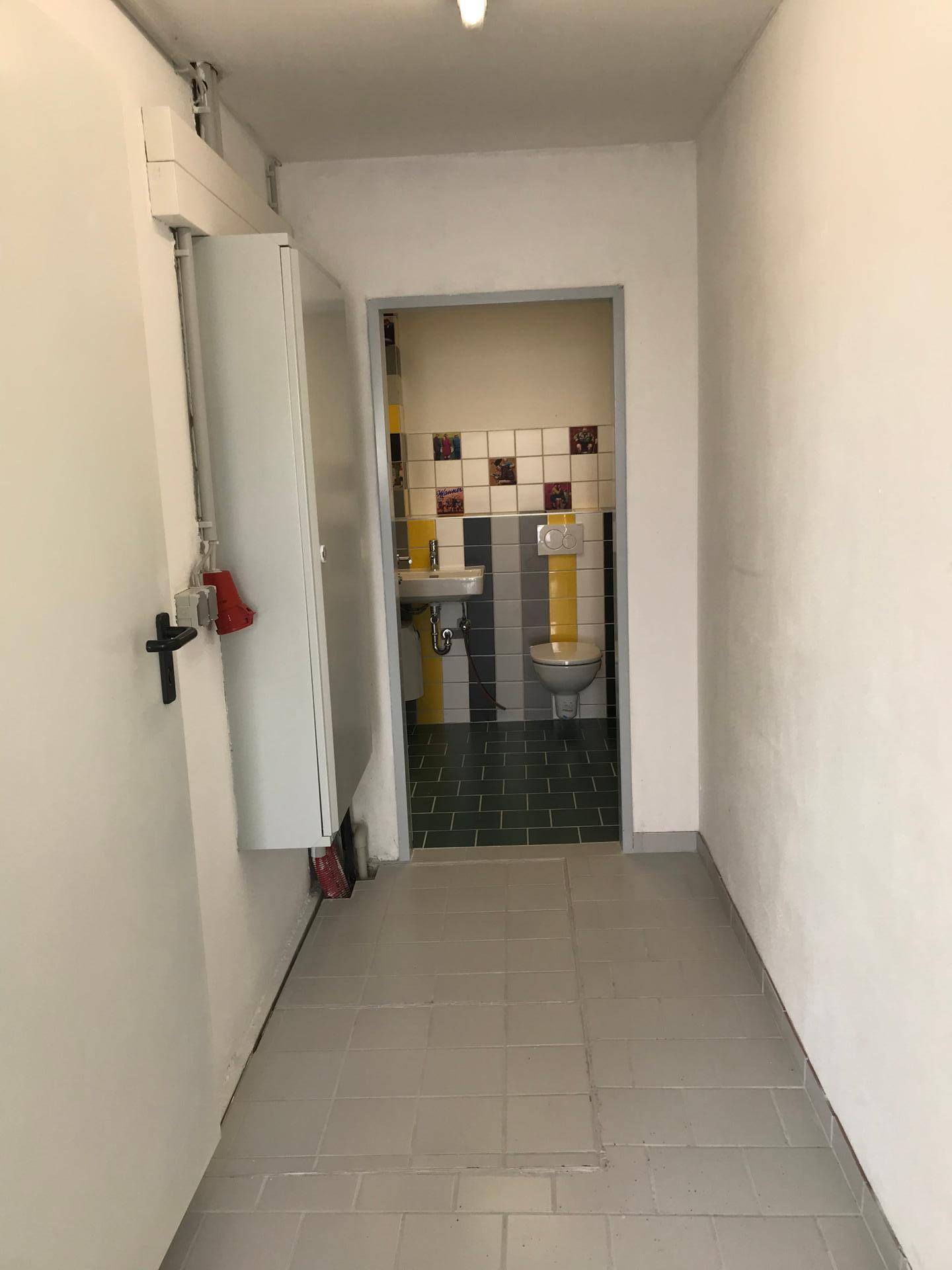Eingangsbereich mit Fliesenboden und Blick auf das farbenfrohe Gäste-WC.