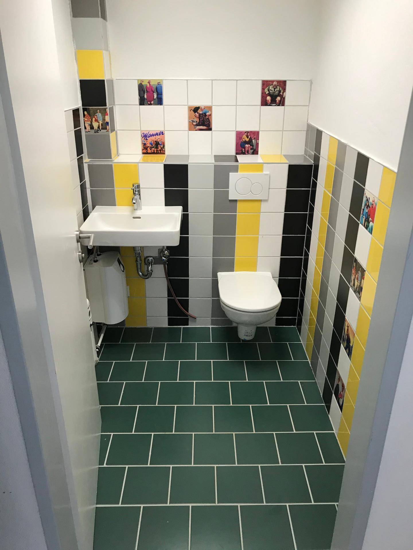 Modernes Gäste-WC mit farbigen Fliesen, Waschbecken und wandhängendem WC.