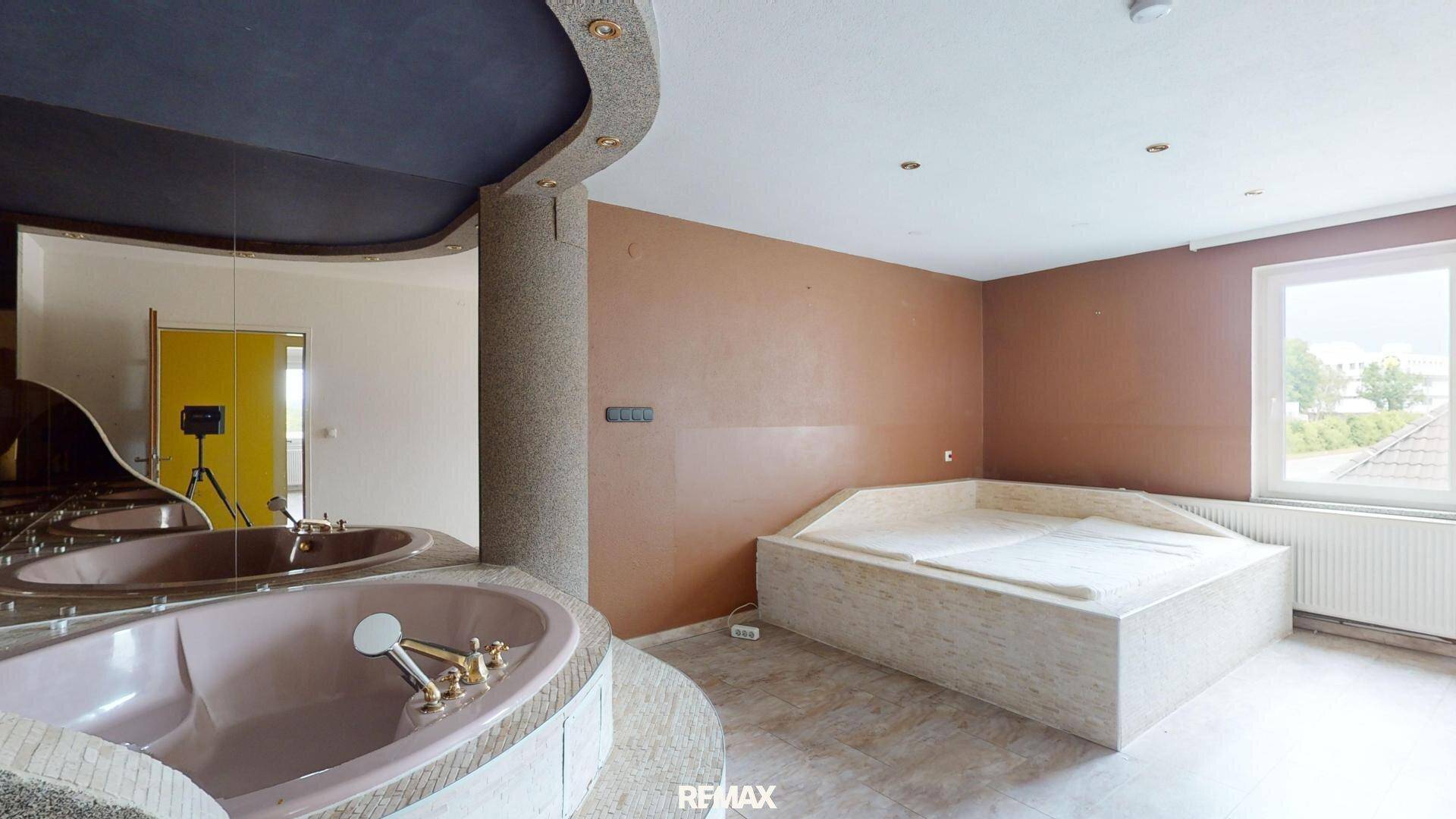 Geräumiger Spa-Raum mit zwei großen Badewannen, einer Spiegelfläche und einer auffälligen Deckenfarbe.