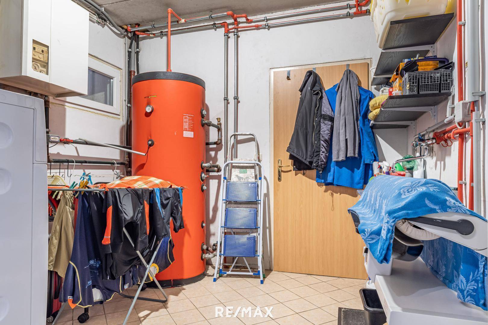 Praktischer Hauswirtschaftsraum im Keller mit Warmwasserspeicher, Waschbereich und Stauraum.