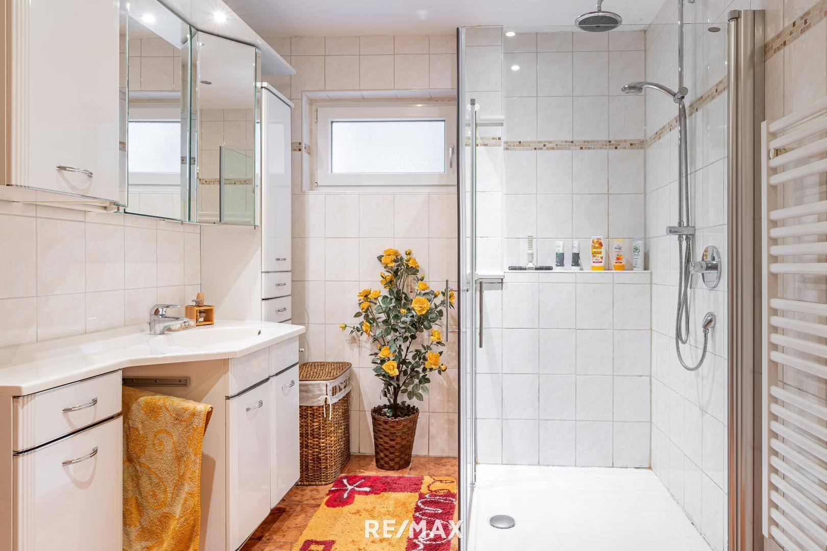 Modernes Badezimmer mit ebenerdiger Dusche, Einzelwaschbecken und beheiztem Handtuchhalter.