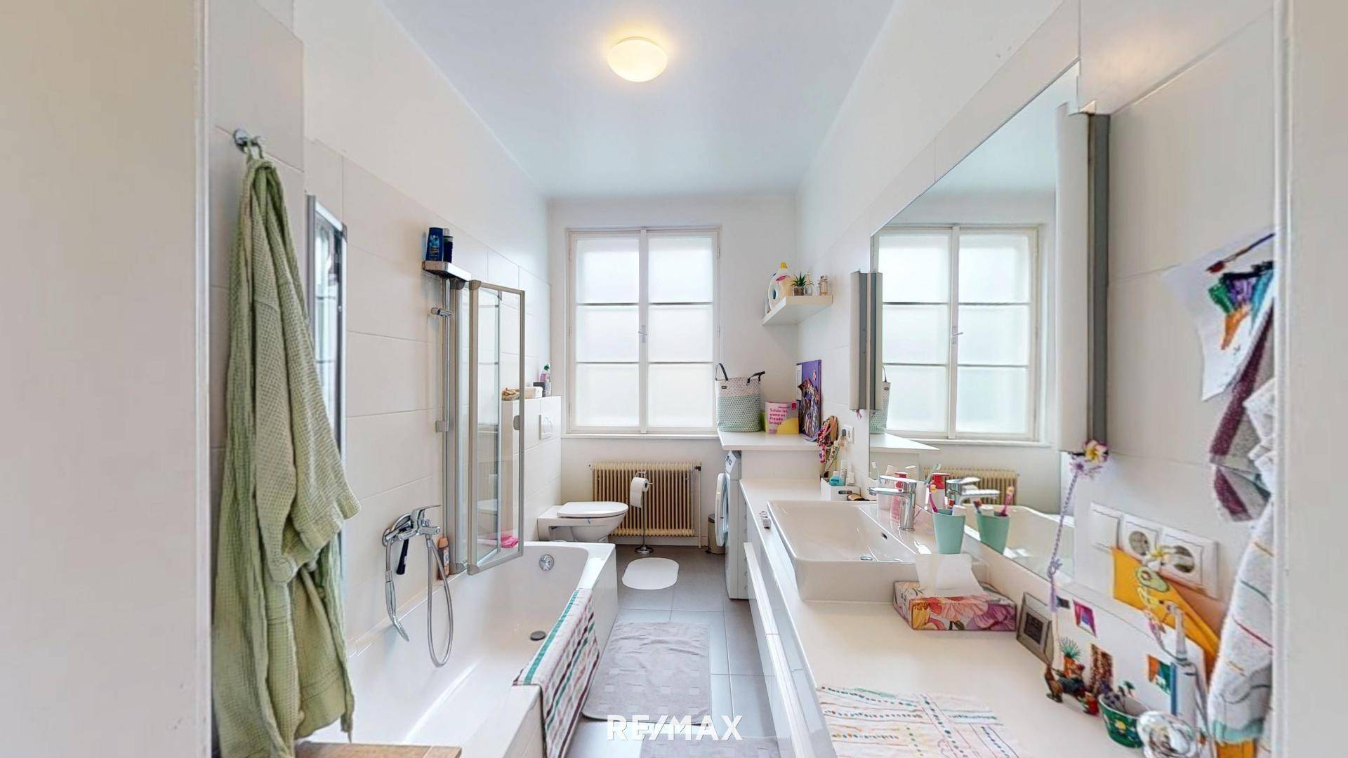 Helles Badezimmer mit Badewanne, Dusche, Doppelwaschbecken und Fenster.