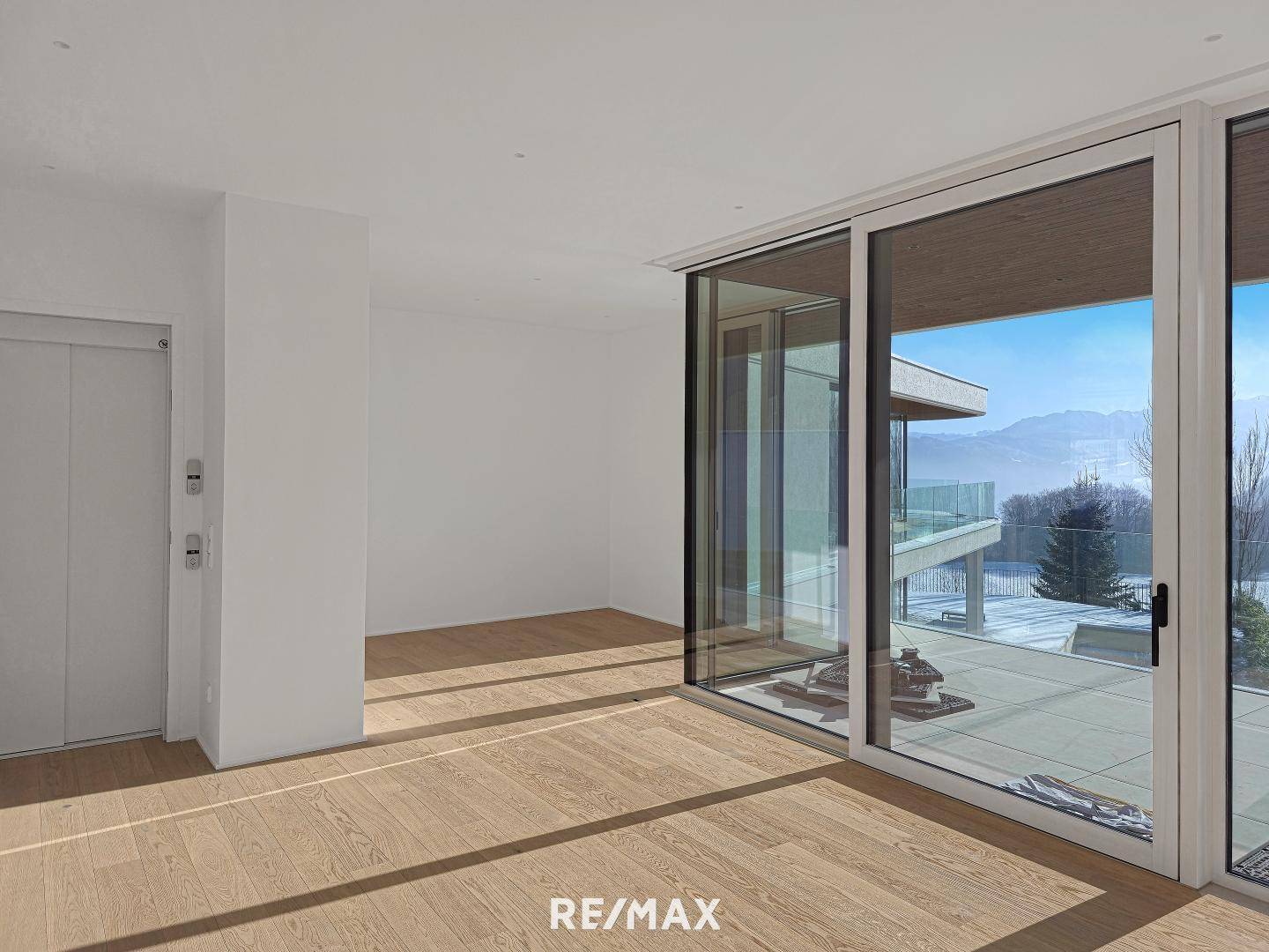 Heller Raum mit Holzboden, großen Fenstern und einem integrierten Aufzug für Komfort.