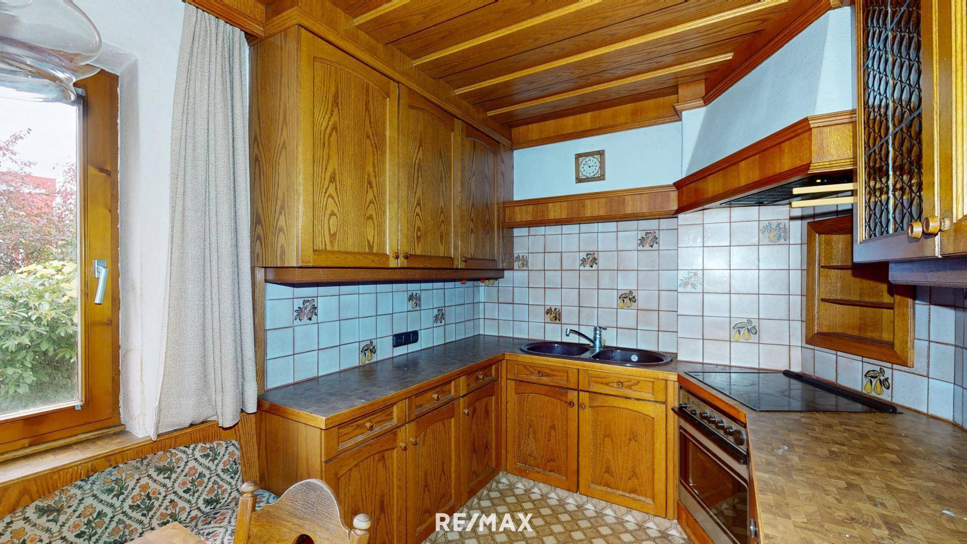 Traditionelle Holzküche mit blauen Fliesen und einem Fenster mit Blick ins Grüne.