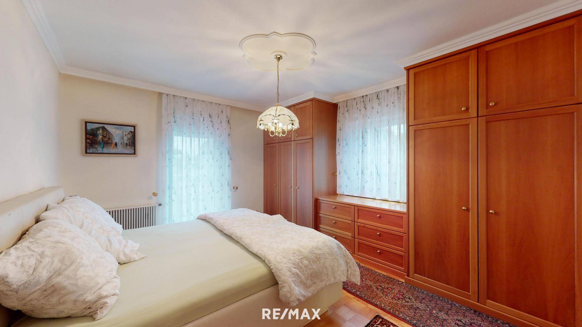 Schlafzimmer mit Holzeinbauschränken, Parkettboden und Stuckdecke.