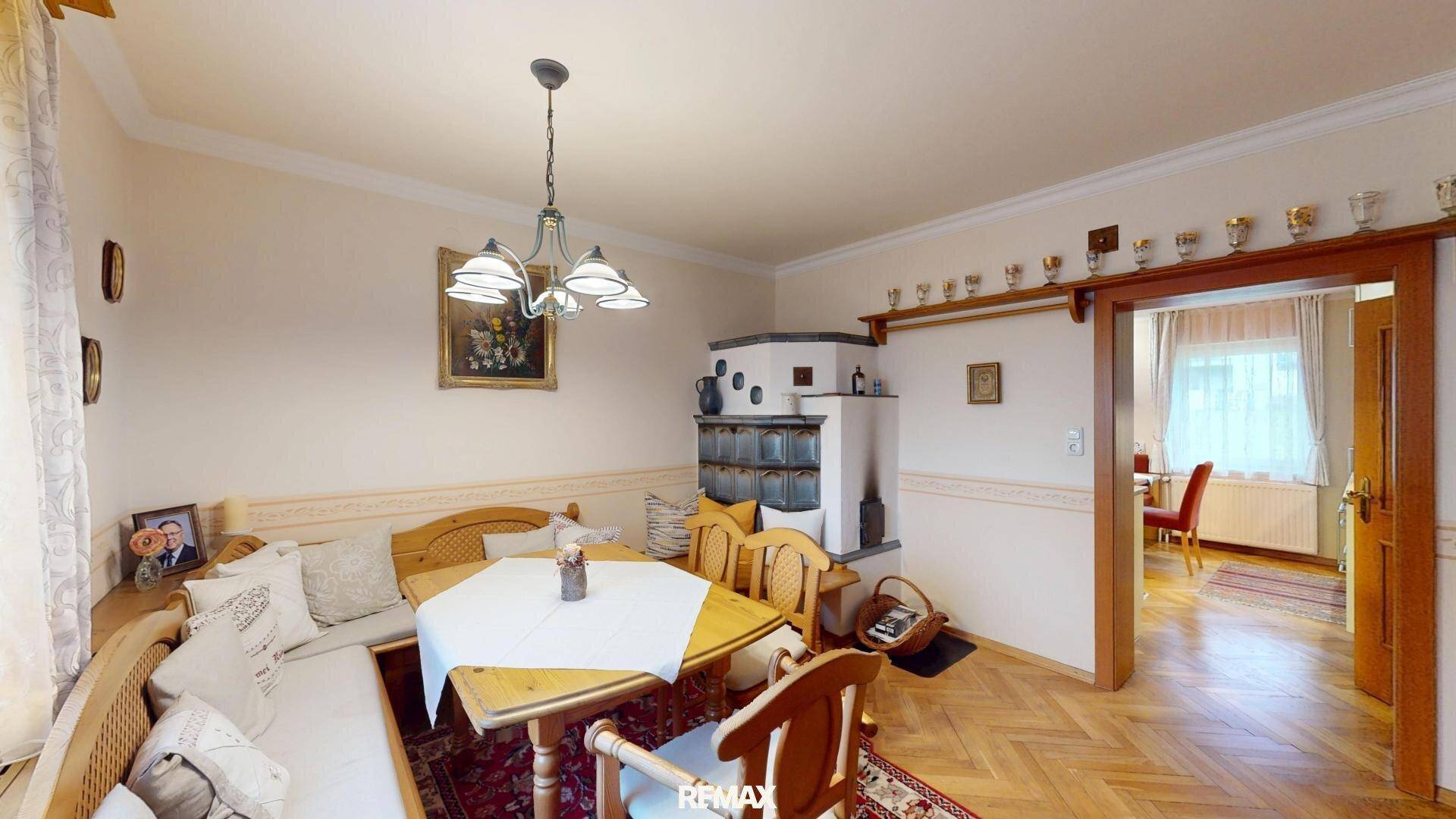 Gemütlicher Essbereich mit traditionellem Kachelofen und Holzbänken, ideal für Familienessen.