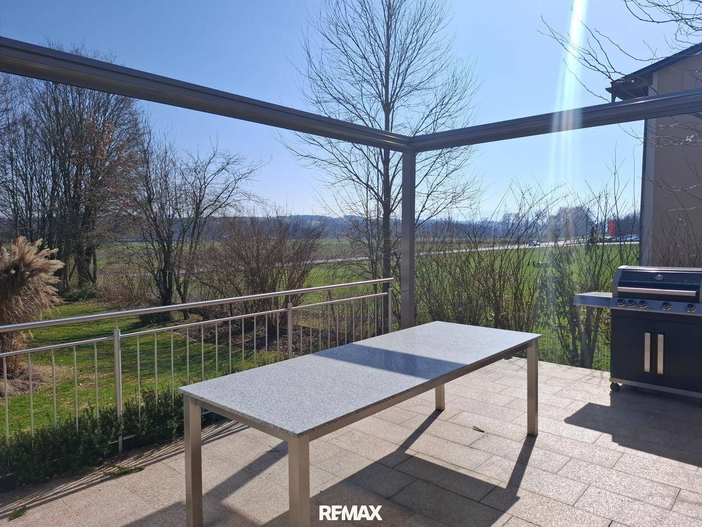 Überdachte Terrasse mit großem Esstisch und Grillbereich, ideal für Mahlzeiten im Freien.