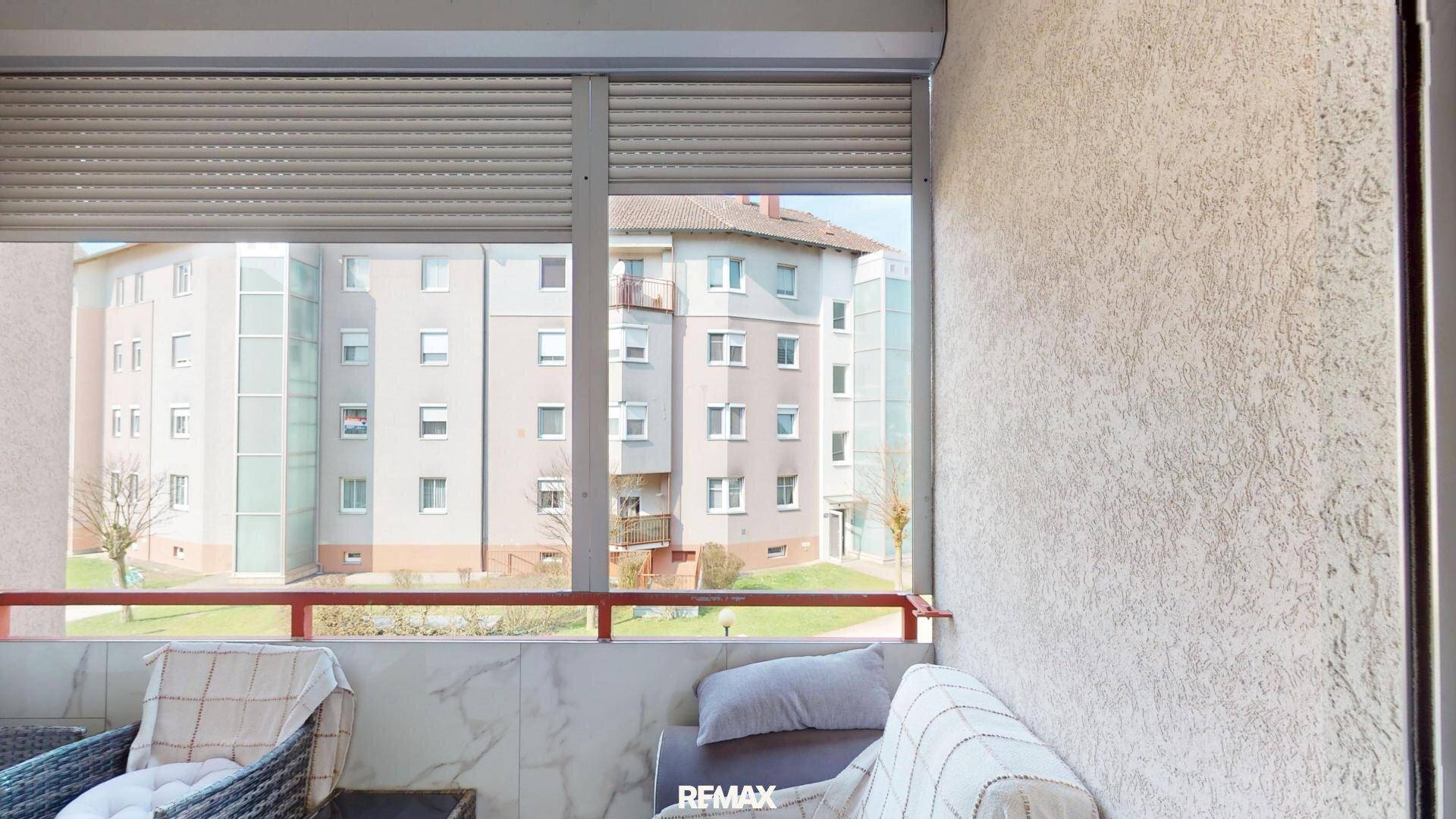 Balkon mit Sitzgelegenheiten und Blick auf die umliegenden Gebäude.