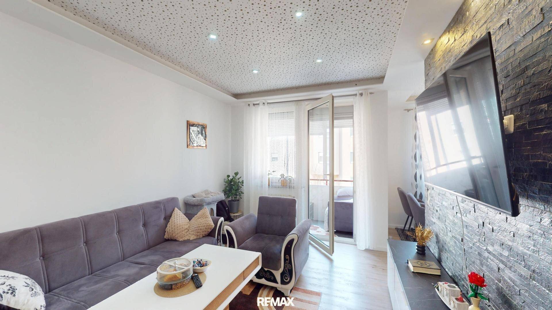 Gemütliches Wohnzimmer mit Balkonzugang, Sofa und dekorativer Steinwand.