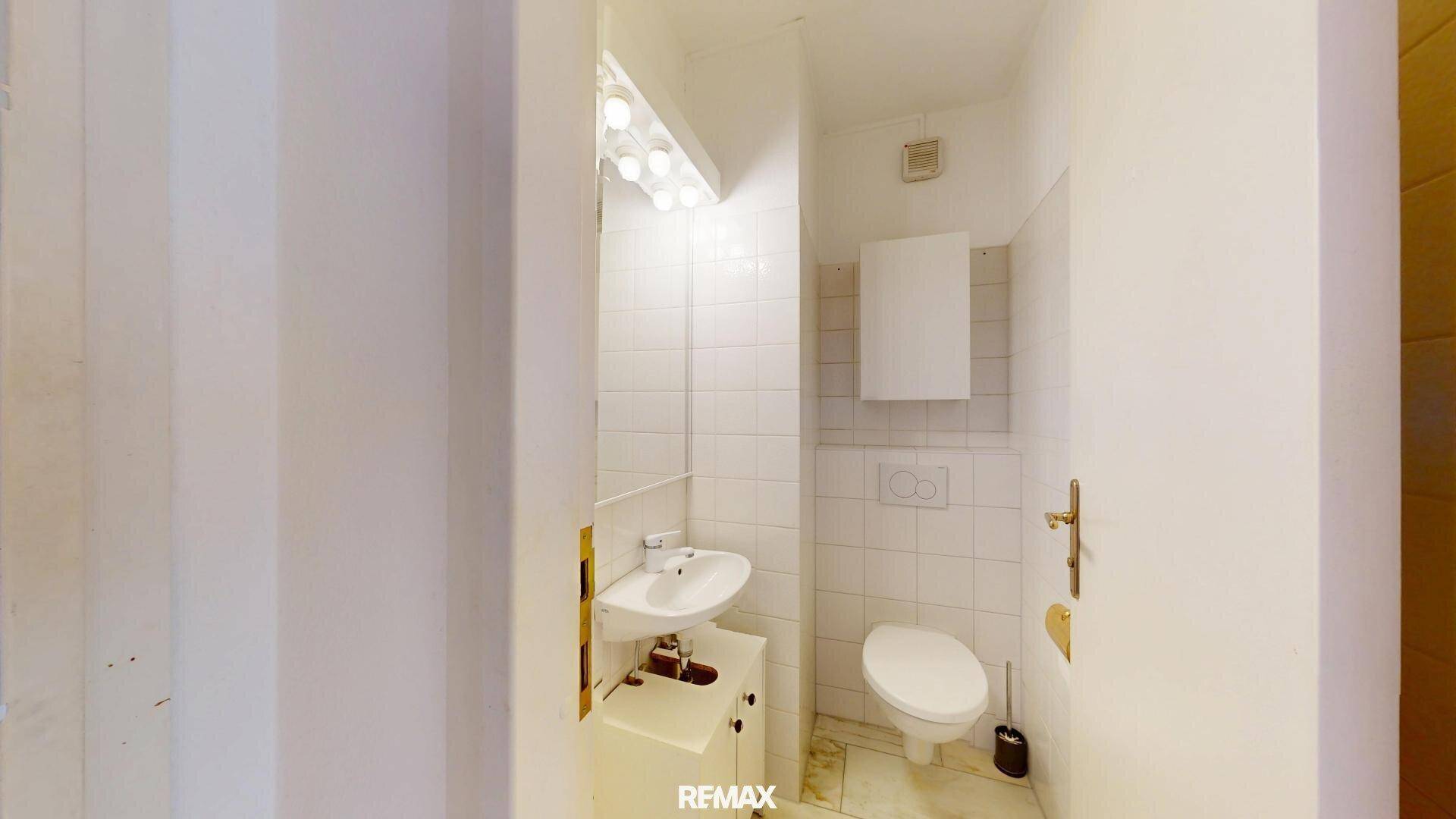 Kleines Gäste-WC mit Waschbecken, Toilette und weißen Fliesen.