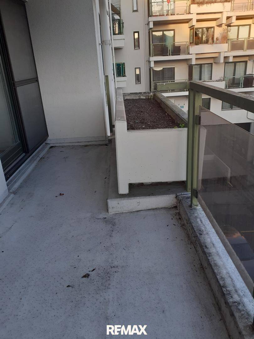 Kleiner Balkon mit Betonboden und Blick auf benachbarte Wohngebäude.