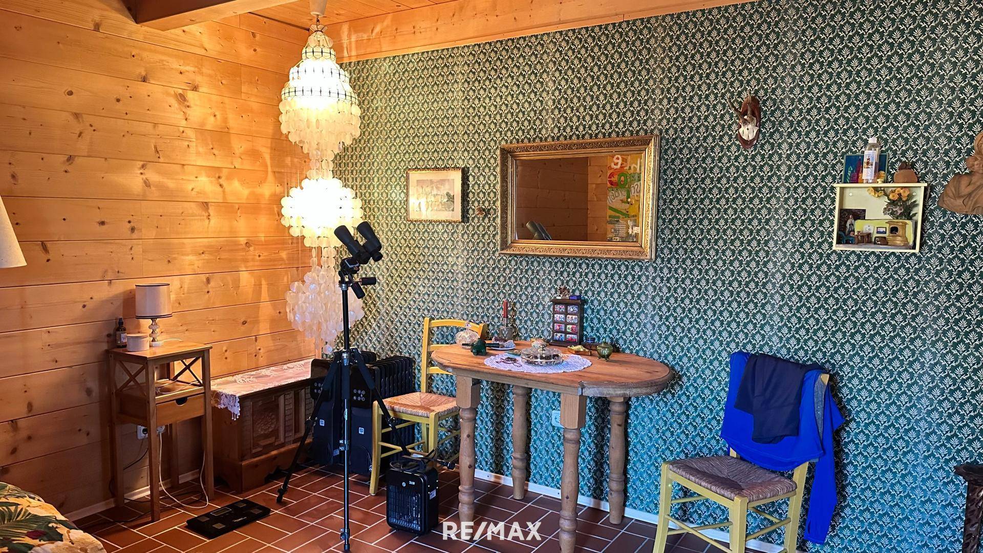 Essbereich mit gemusterter Tapete, einem rustikalen Holztisch und traditionellen Stühlen.