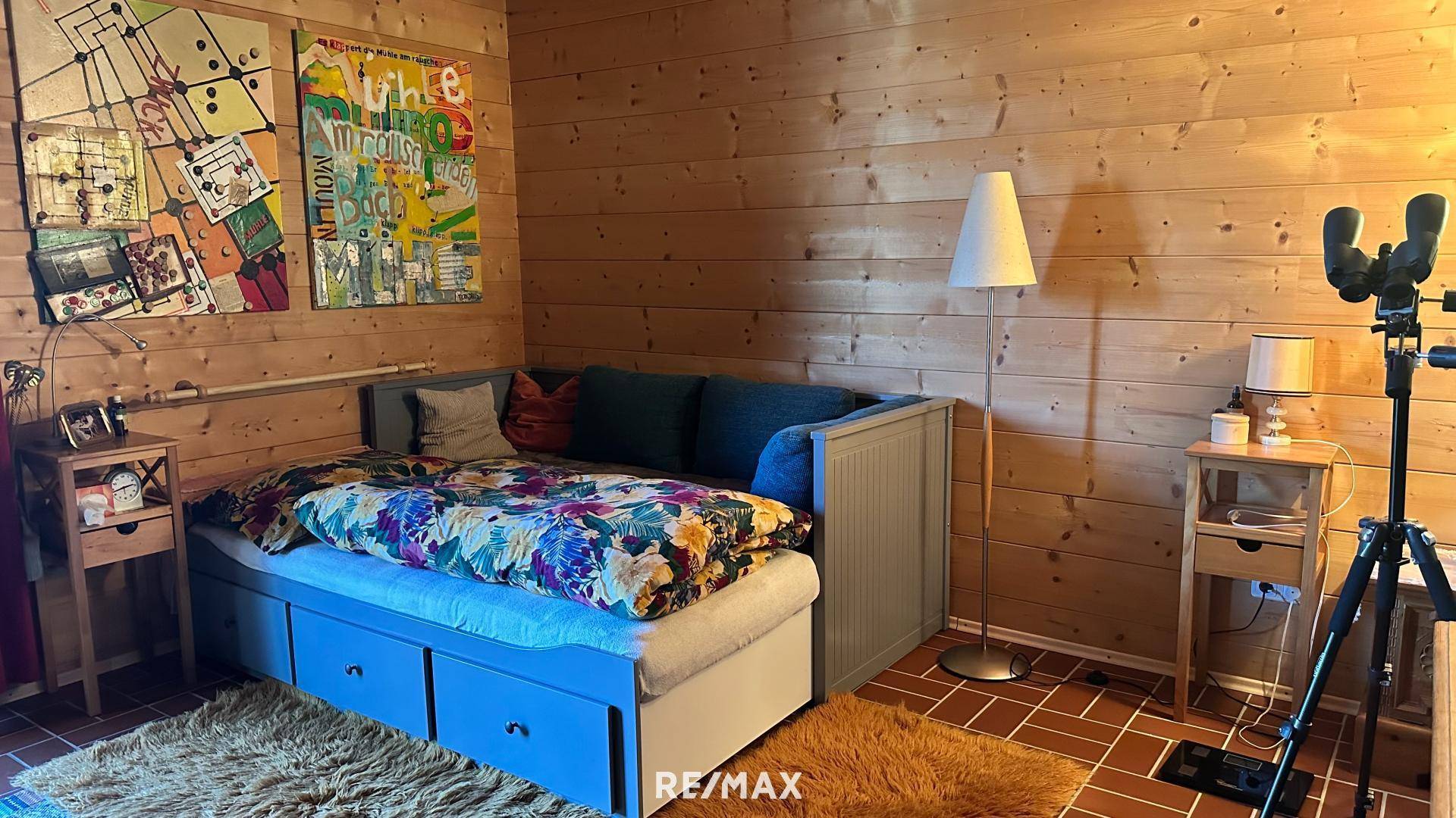 Schlafzimmer mit Holzwänden, einem Einzelbett mit Stauraum und farbenfroher Dekoration.