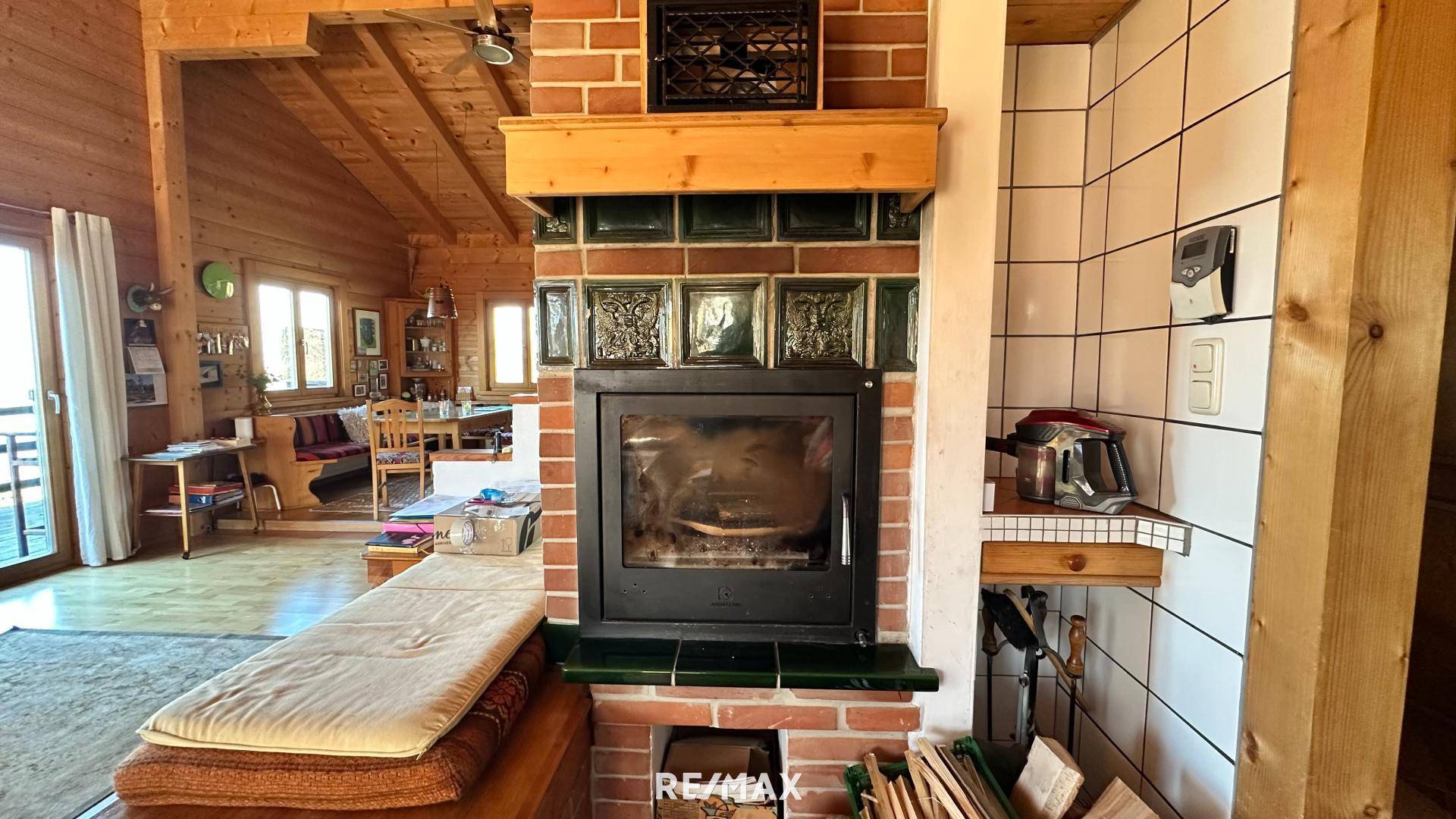 Detailansicht eines traditionellen Kamins mit Ziegel- und Kachelelementen in einem Holzhaus.