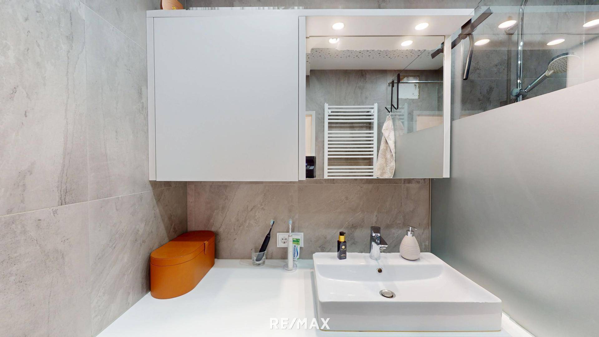 Modernes Badezimmer mit Waschtisch, Spiegel und integriertem Medizinschrank.