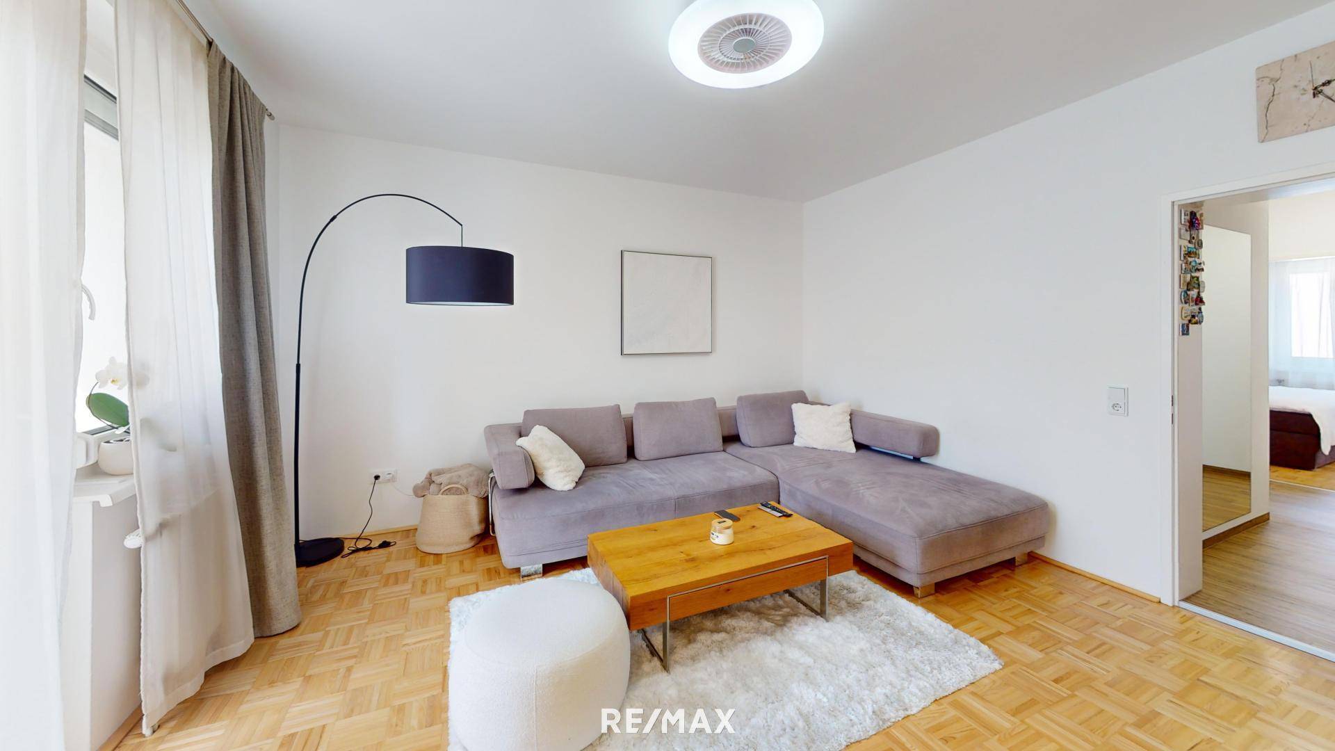 Helles Wohnzimmer mit Ecksofa, Couchtisch und Parkettboden.