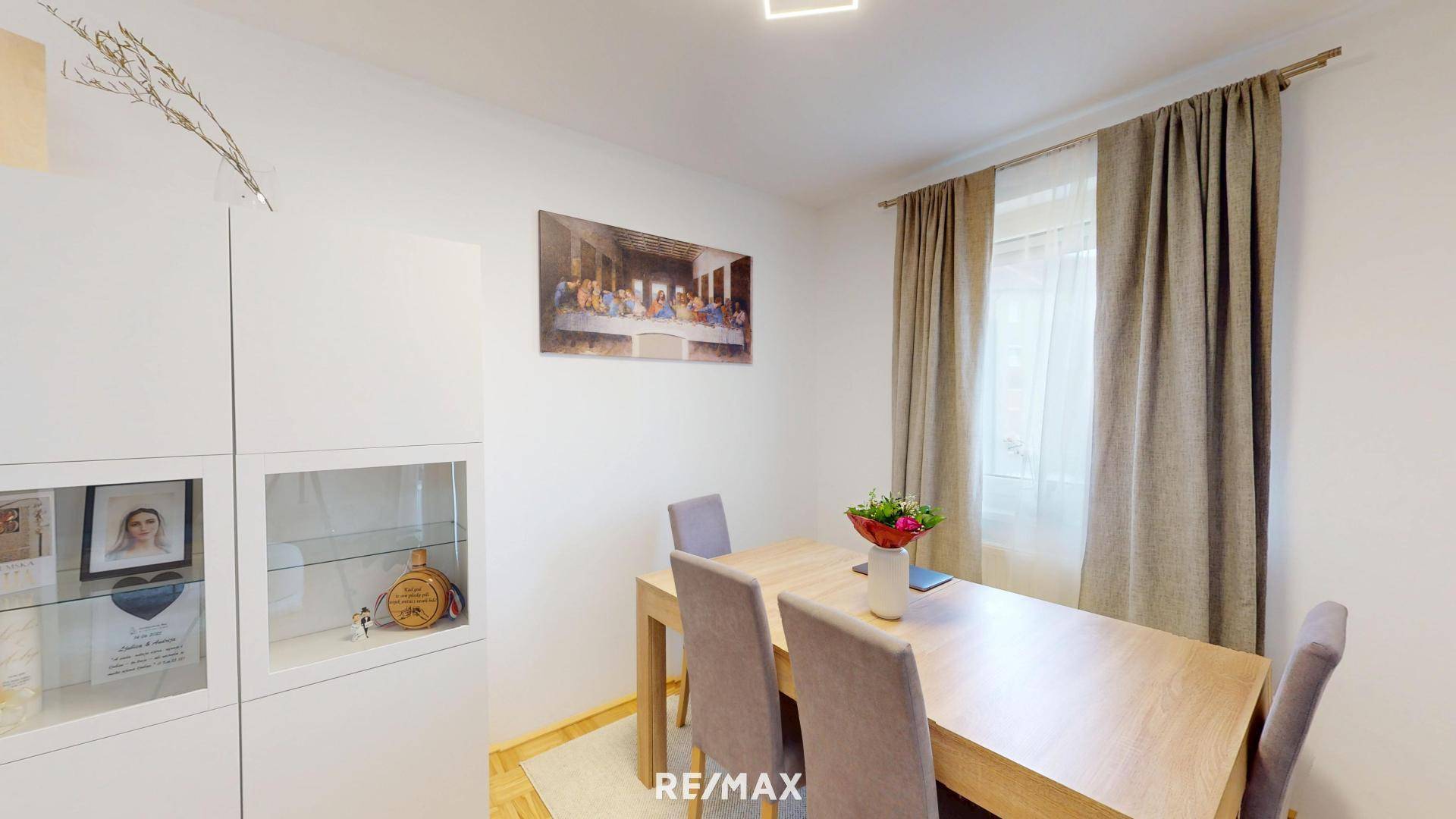 Gemütlicher Essbereich mit Holztisch, bequemen Stühlen und Fenster mit Vorhängen.