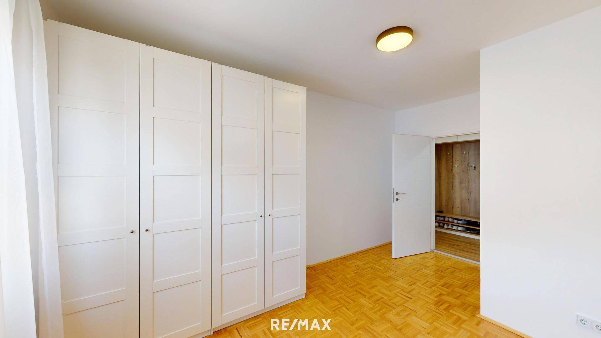 Geräumiges Schlafzimmer mit Parkettboden und großem weißen Kleiderschrank.