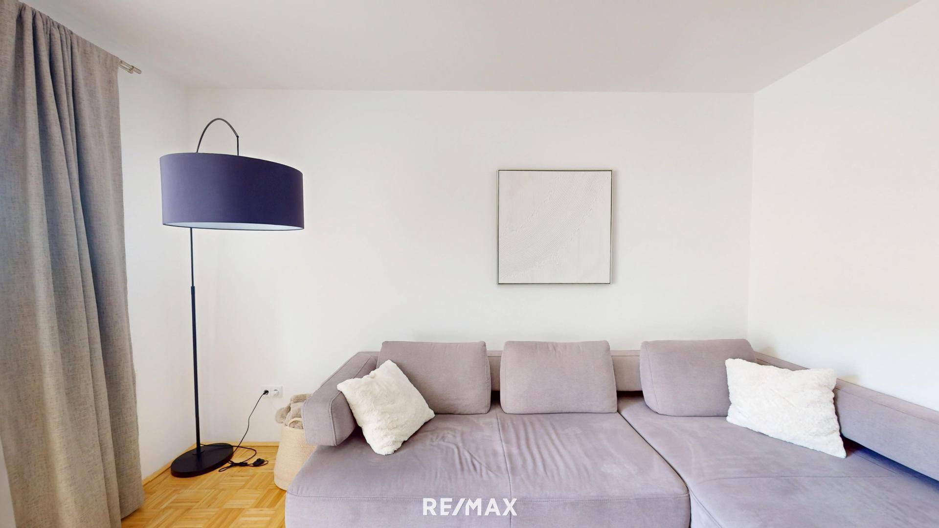 Gemütliches Wohnzimmer mit großem Ecksofa, Stehlampe und Parkettboden.
