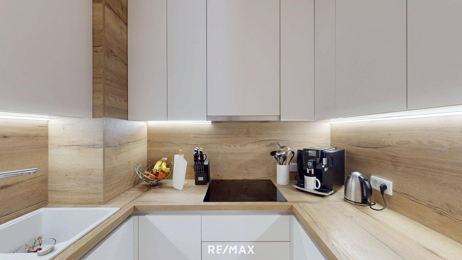 Moderne Einbauküche mit hellen Fronten, Holzdetails und Induktionskochfeld.
