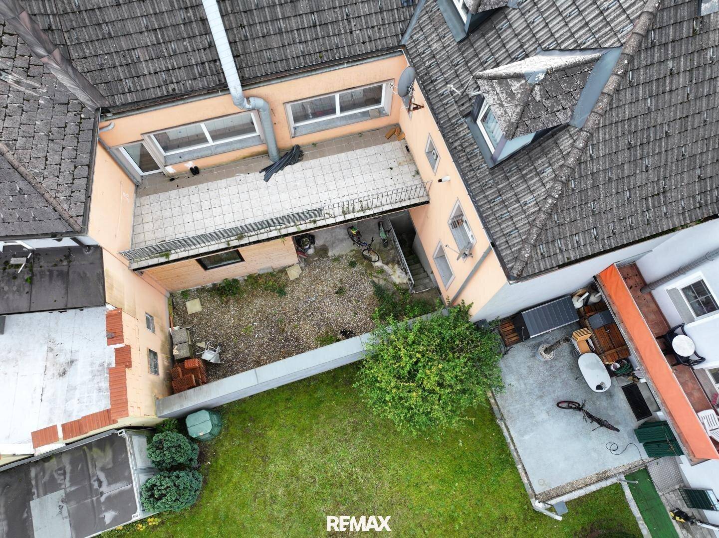 Luftaufnahme des Hinterhofs mit einer gepflasterten Terrasse und einem kleinen Gartenbereich.