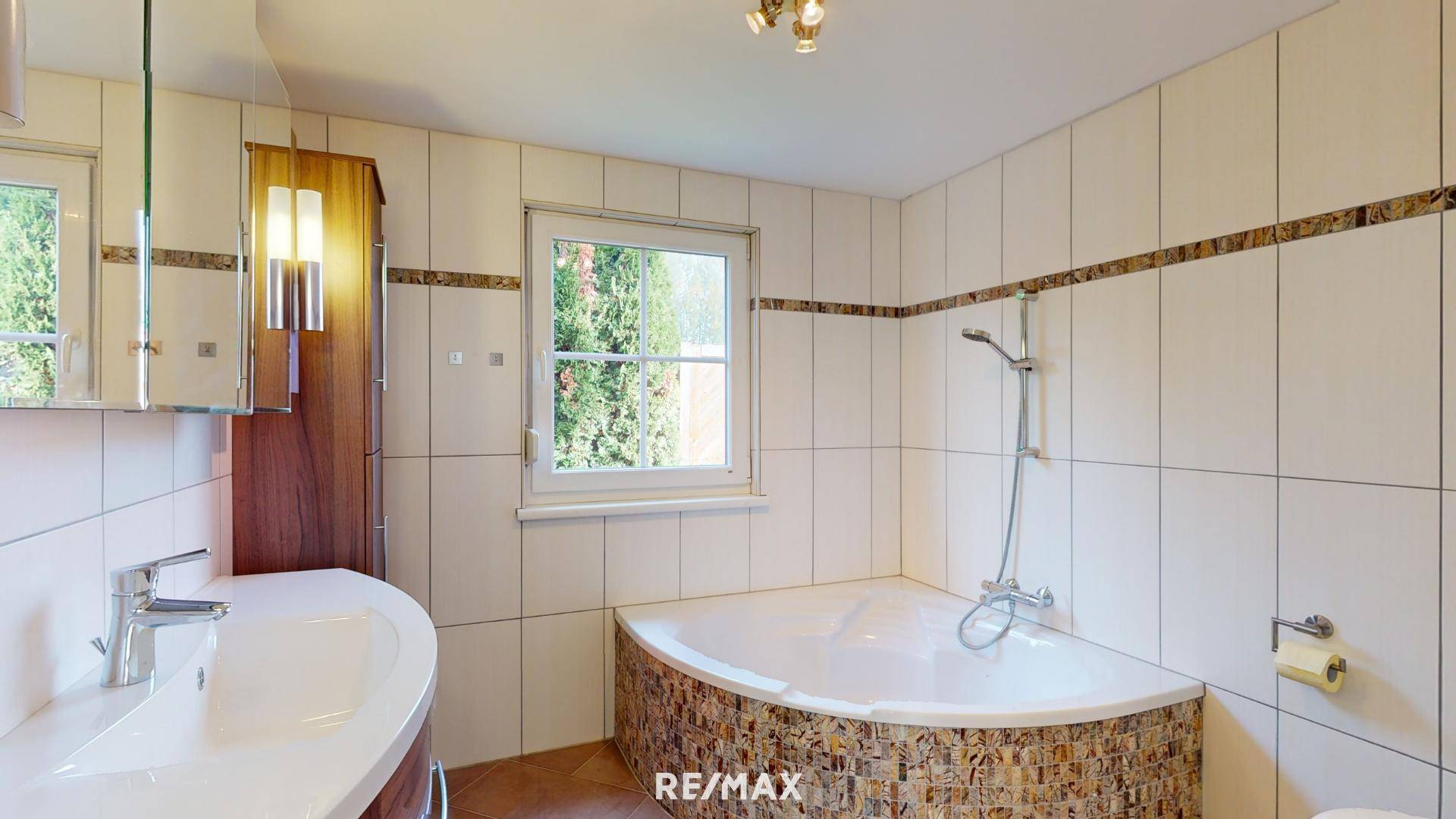 Modernes Badezimmer mit Eckbadewanne, Fliesen und einem Fenster für natürliches Licht.