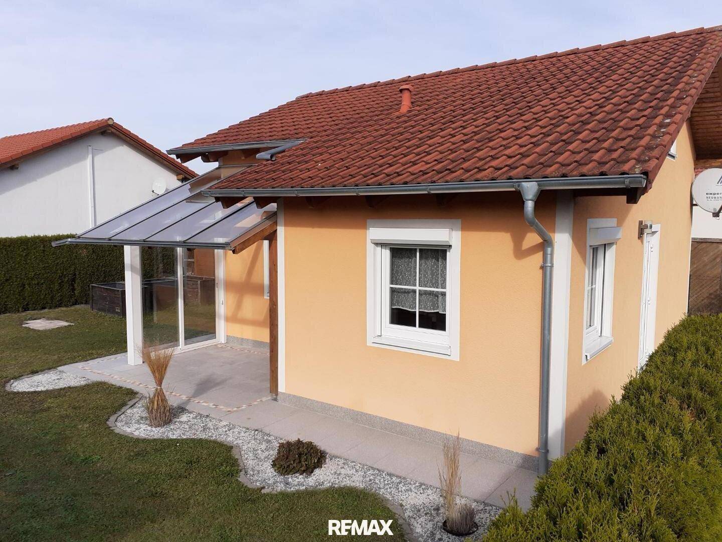 Seitenansicht des Hauses mit überdachtem Terrassenbereich und kleiner Gartenanlage.