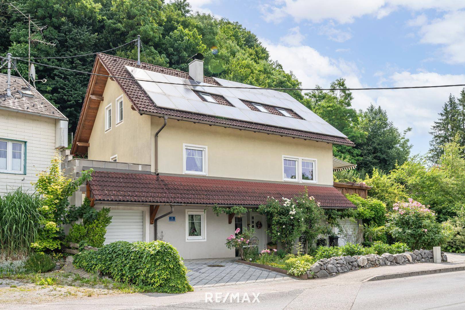 Ansicht des Hauses von der Straße mit Solarpaneelen auf dem Dach und gepflegtem Vorgarten.