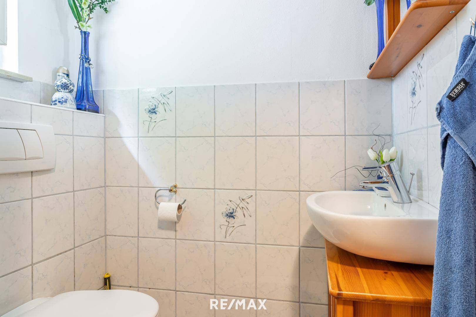 Kleines Gäste-WC mit Wandfliesen, Einzelwaschbecken und einem Fenster für Tageslicht.