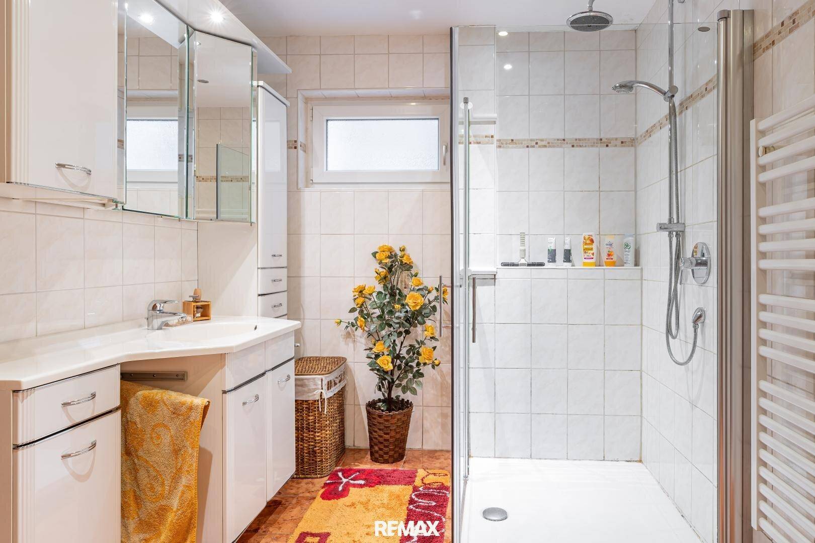 Modernes Badezimmer mit ebenerdiger Dusche, Einzelwaschbecken und beheiztem Handtuchhalter.