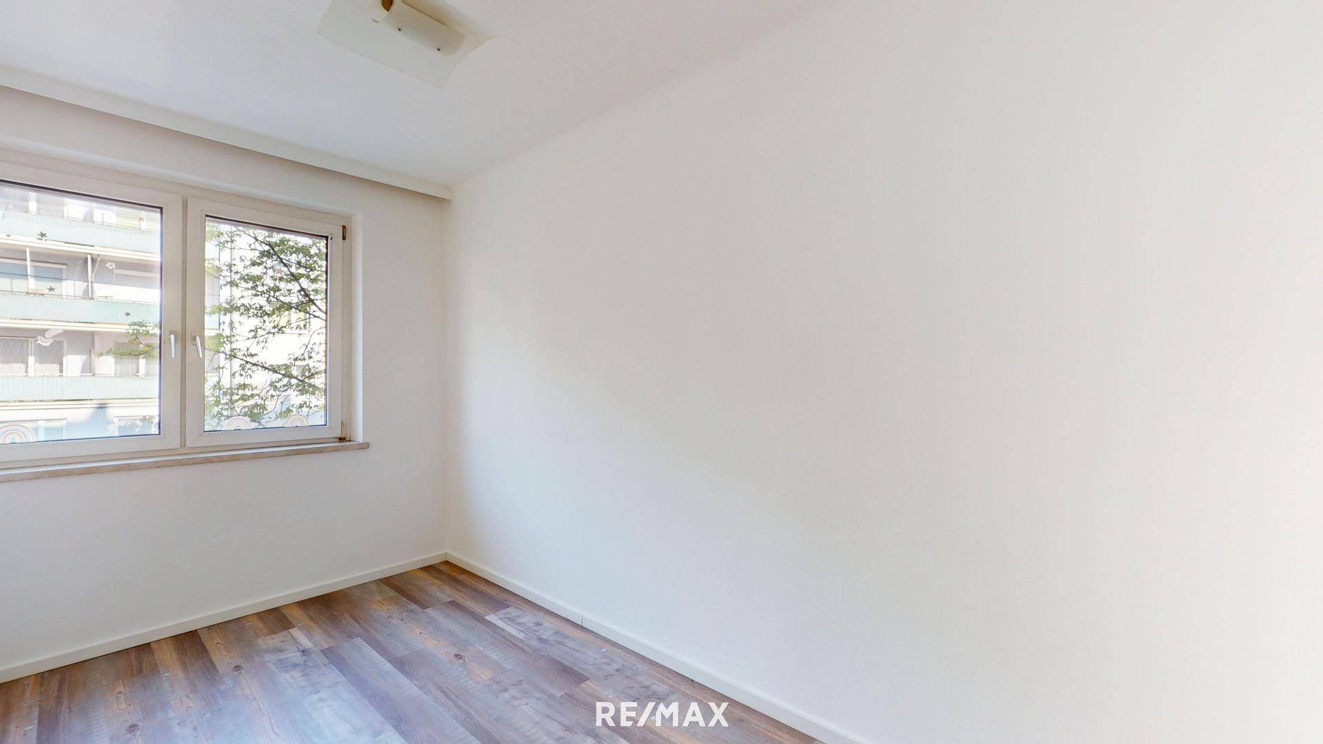 Schlafzimmer mit modernem Laminatboden und großem Fenster für natürliche Belichtung.