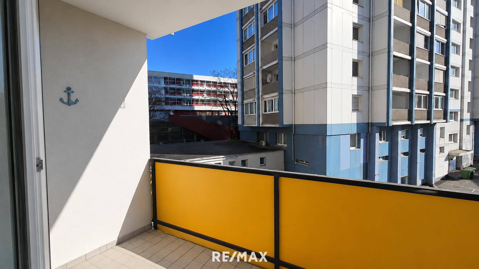 Geräumiger Balkon mit gelbem Geländer und Blick auf die umliegenden Gebäude.