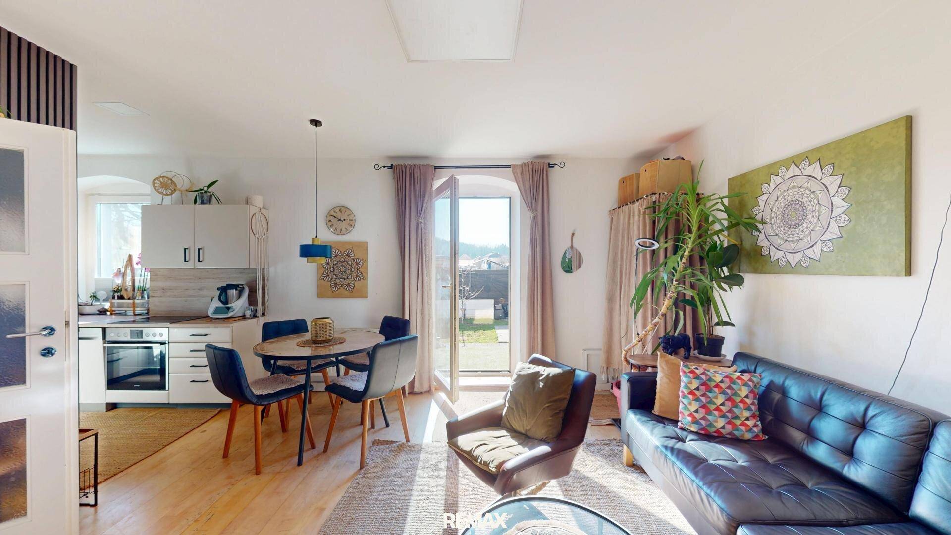 Heller offener Wohn-Essbereich mit integrierter Küche und Zugang zum Garten.