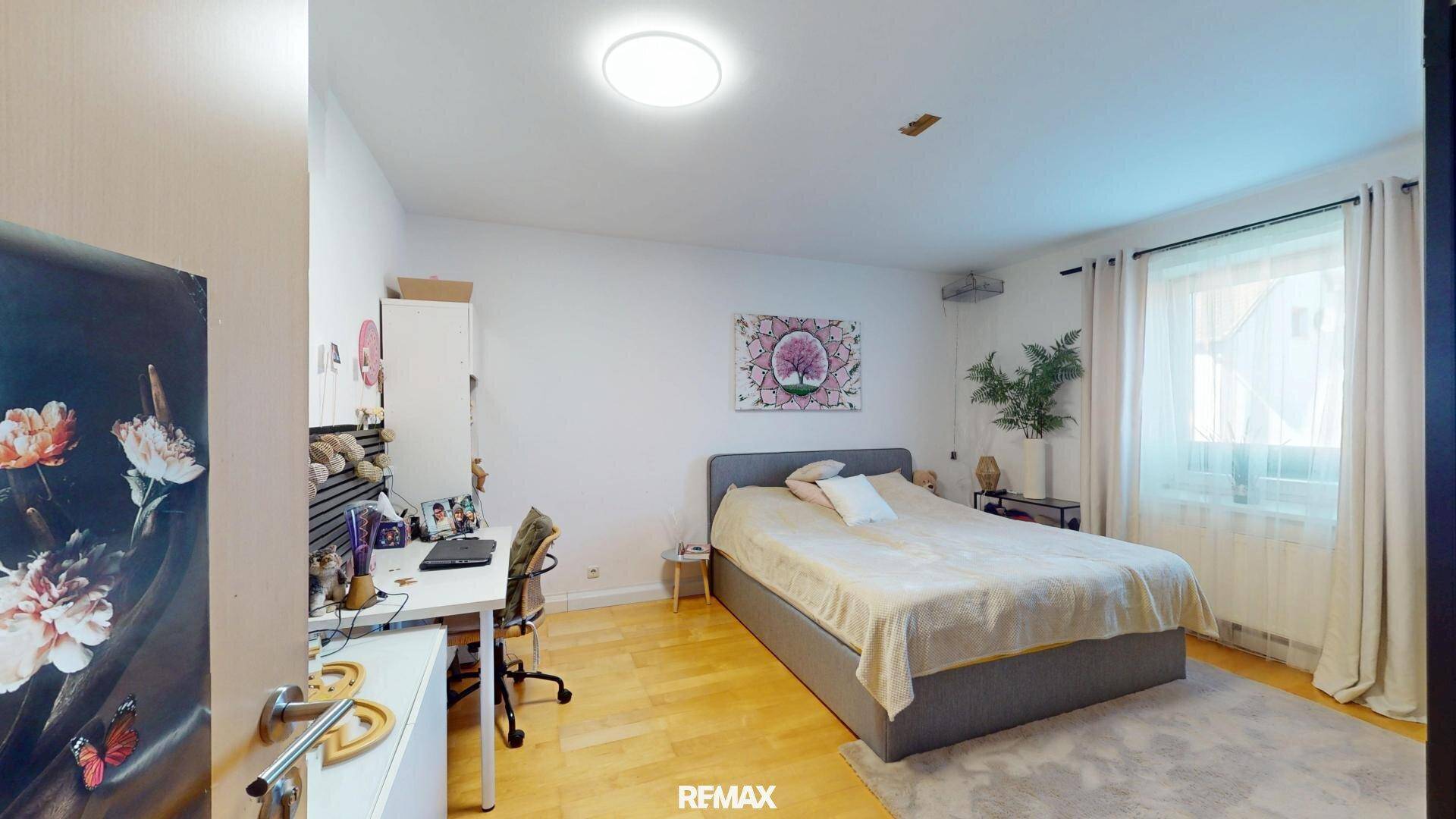 Schlafzimmer mit Doppelbett, Schreibtisch und Holzboden.