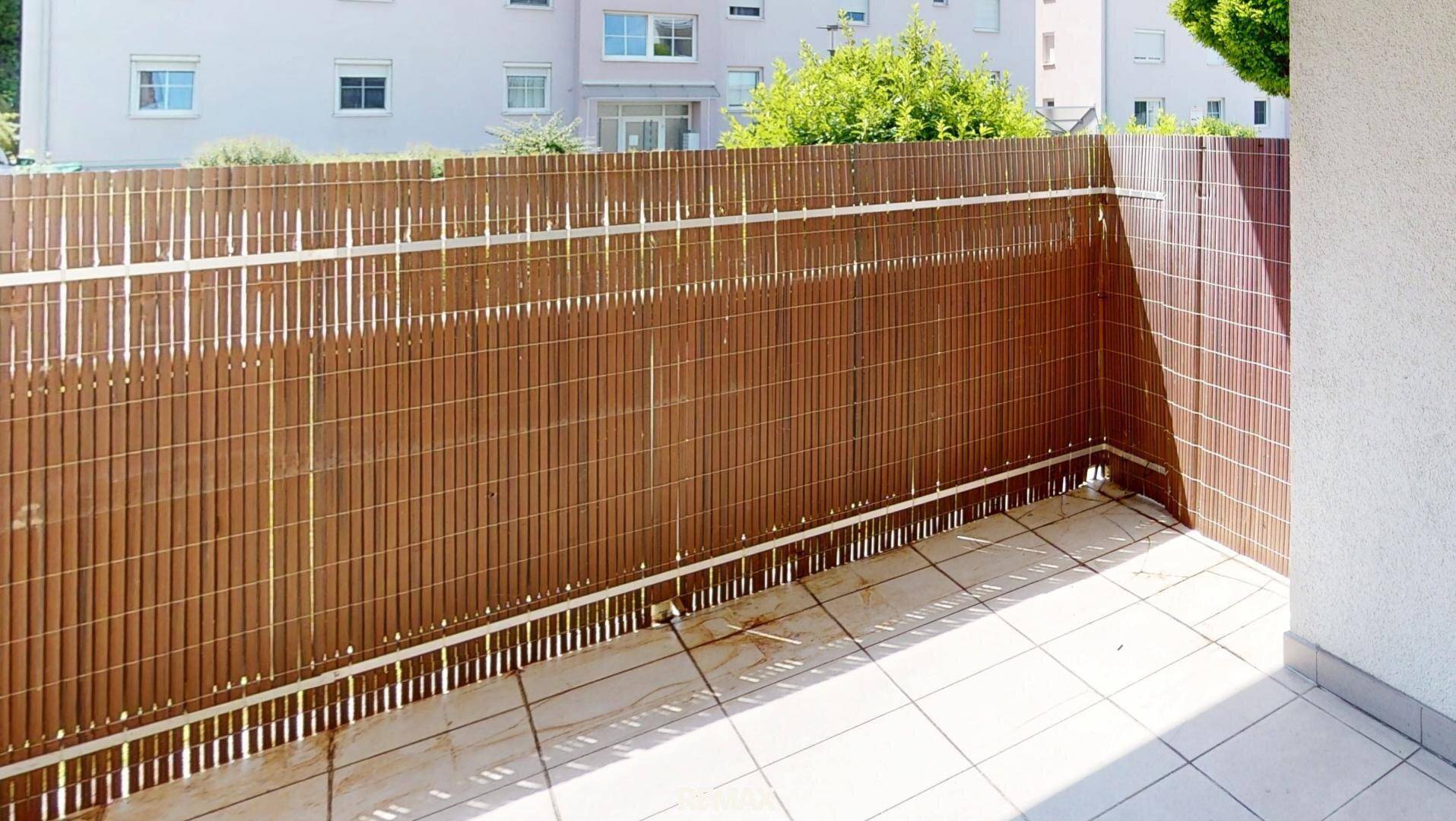 Balkon mit Sichtschutz aus Bambus und Fliesenboden, bietet Privatsphäre im Freien.
