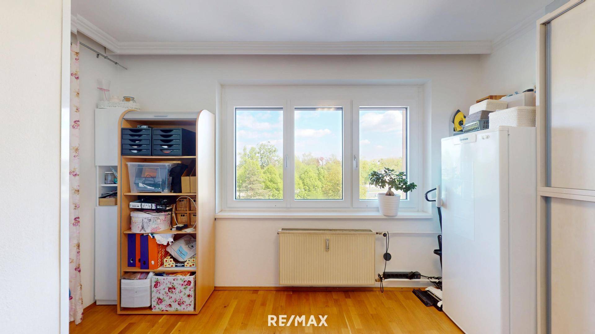 Arbeitszimmer mit Holzboden, großem Fenster und Blick auf die Umgebung.