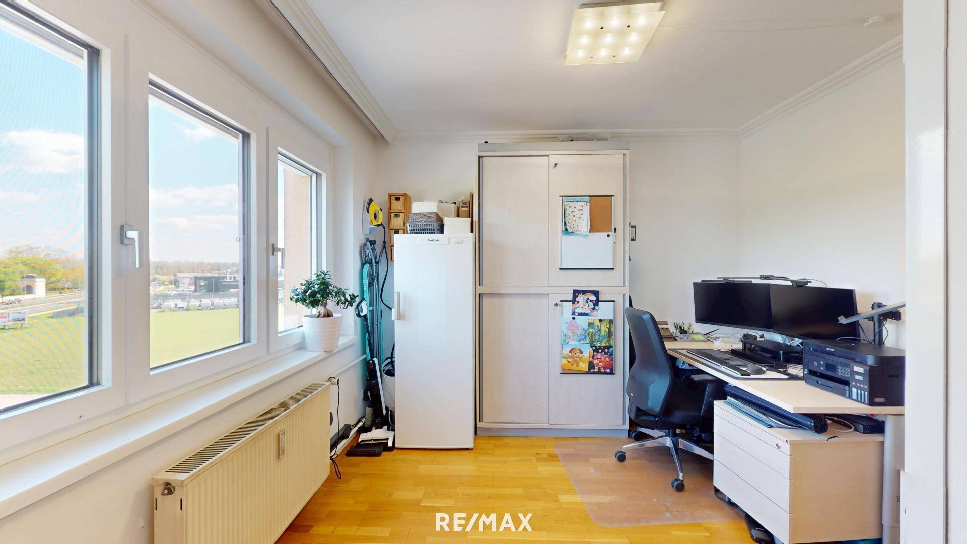 Helles Arbeitszimmer mit großem Fenster, Schreibtisch und Blick ins Grüne.