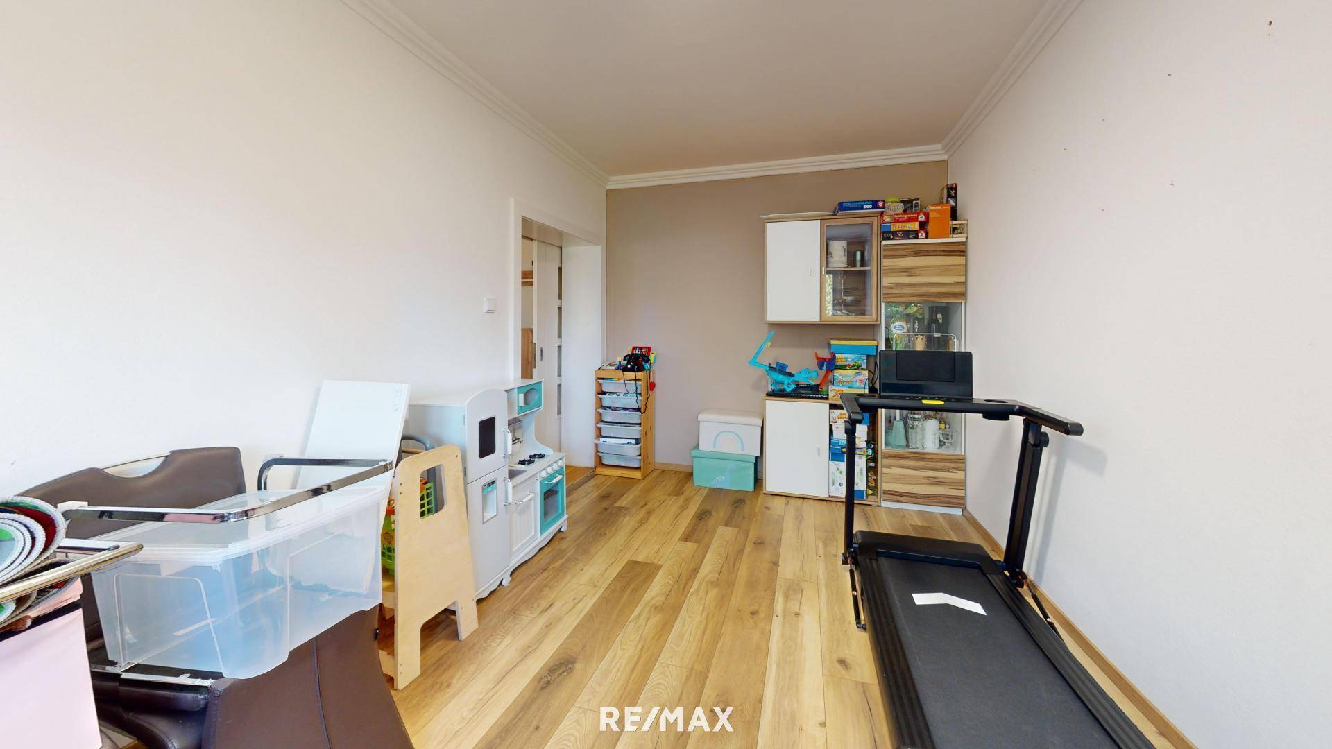 Vielseitig genutzter Raum mit Holzboden, Fitnessgerät und Spielzeug.