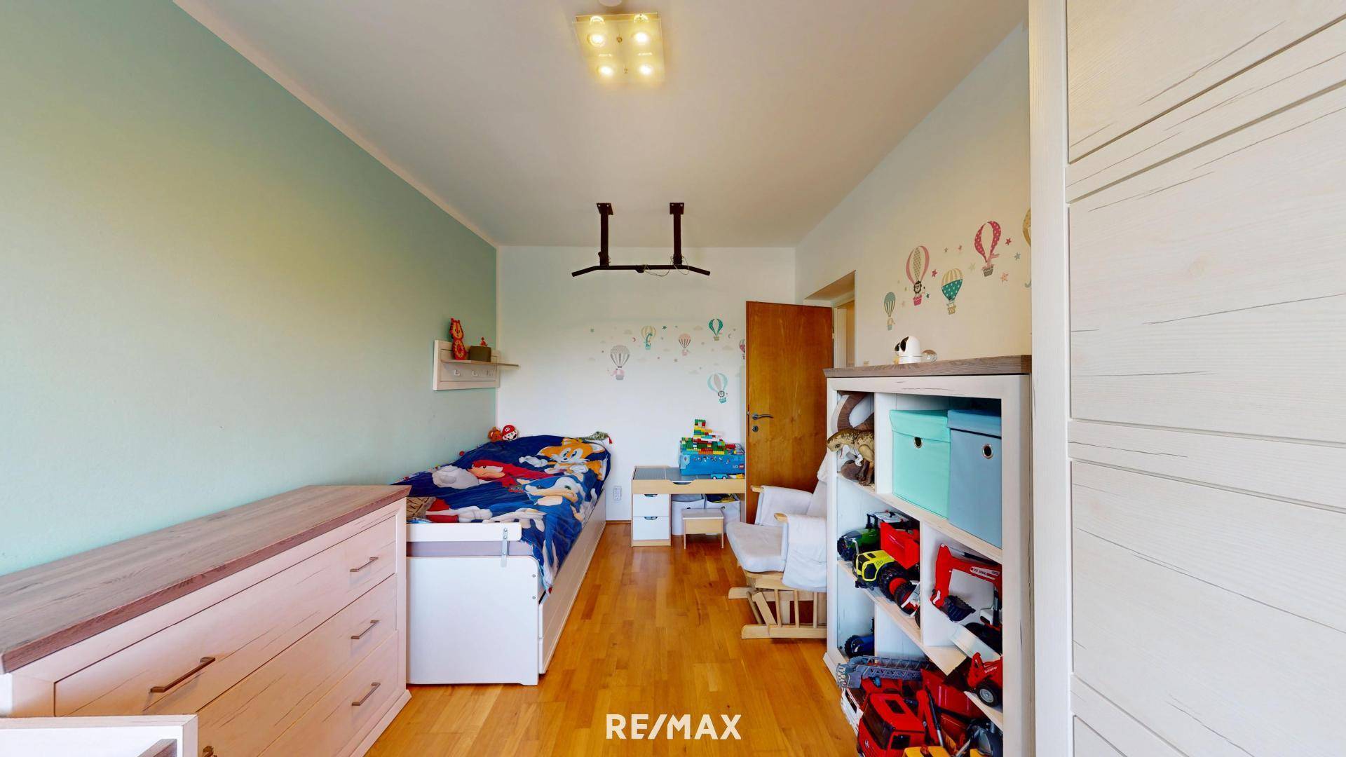 Helles Kinderzimmer mit Einzelbett, Holzboden und verspielter Wanddekoration.