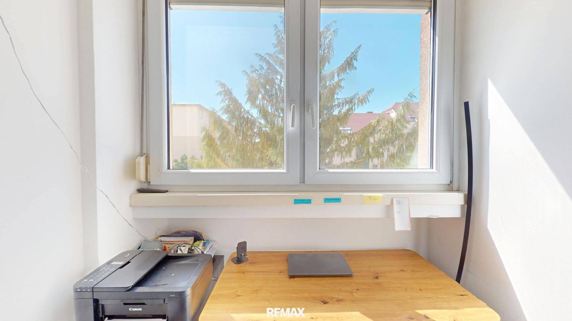 Heller Arbeitsbereich mit Schreibtisch am Fenster und Blick ins Grüne, ideal für Home-Office.