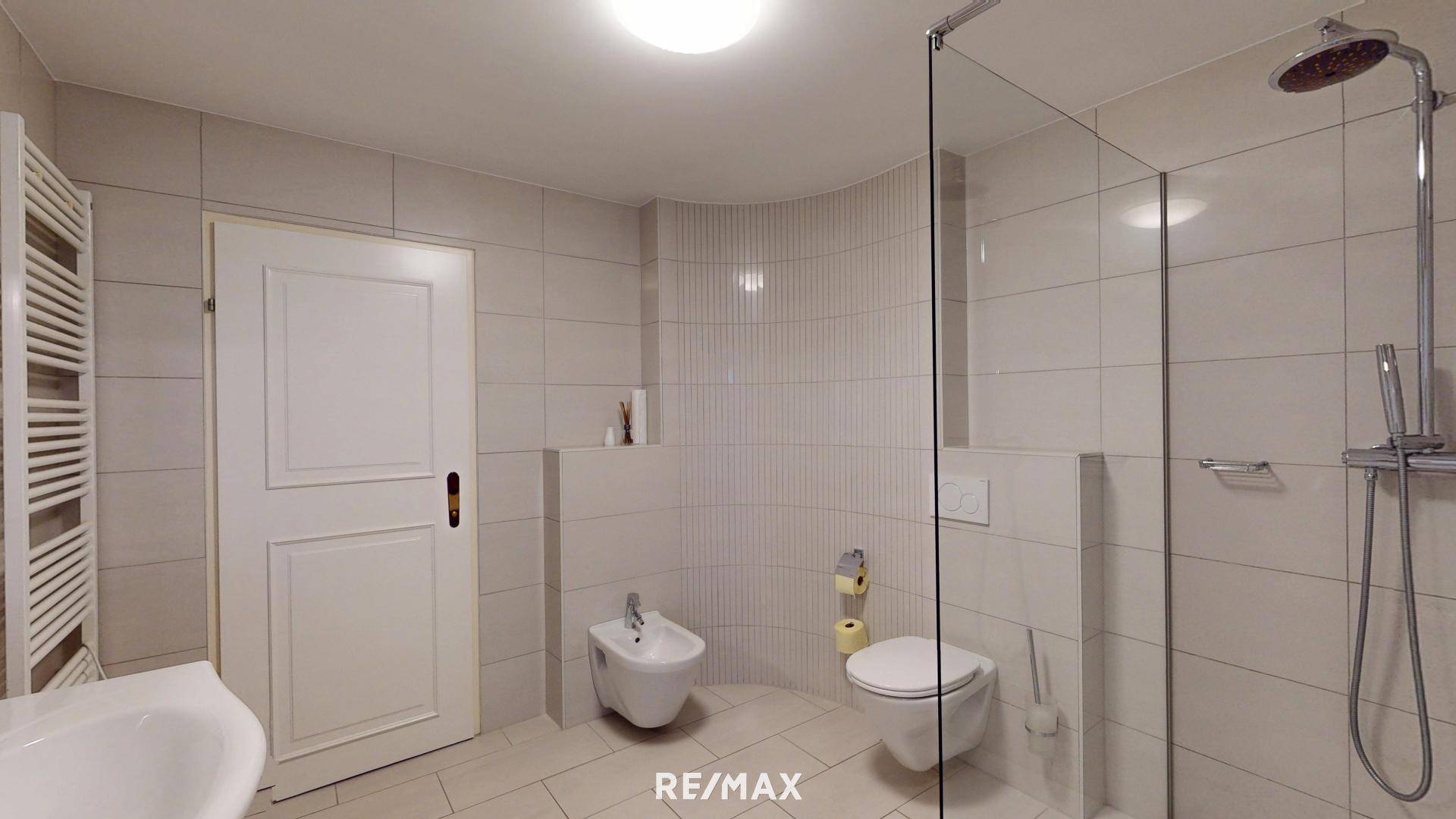 Modernes Badezimmer mit begehbarer Dusche, Bidet und beheiztem Handtuchhalter.